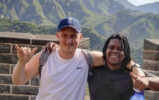 Two teachers locking arms and lookking happy on the Great Wall of China