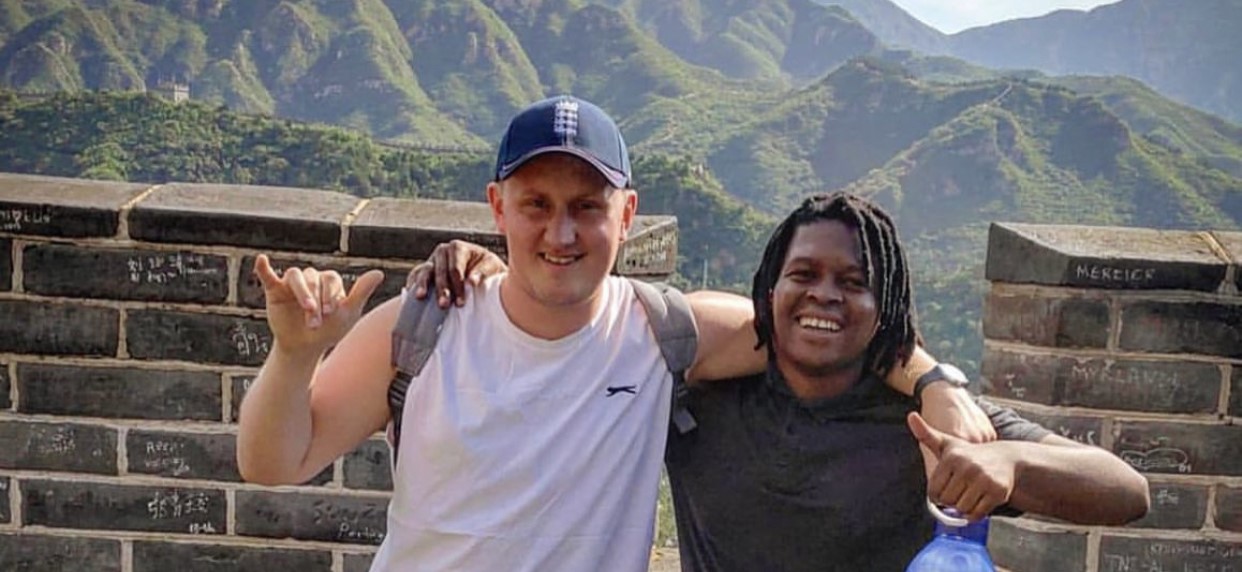 Two teachers locking arms and lookking happy on the Great Wall of China